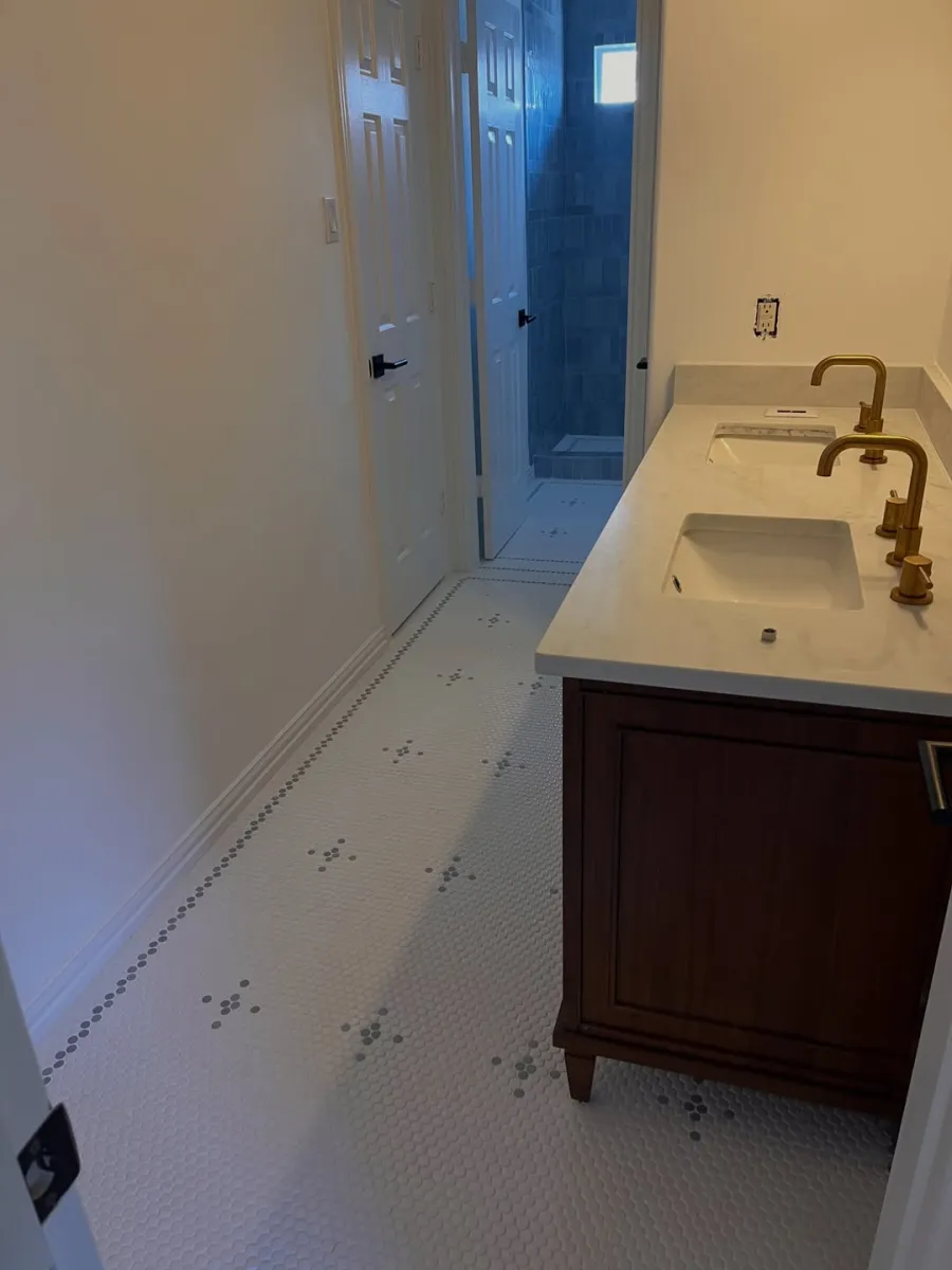 Completed bathroom with detailed mosaic tile floor, double vanity and tiled shower